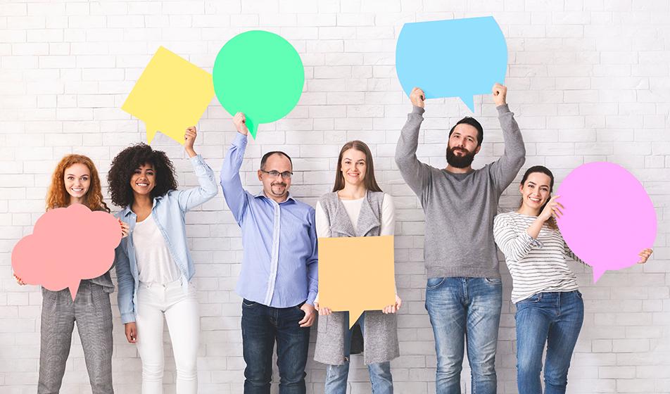 A group of people stand against a white wall in a line, each holding a different coloured speech or thought bubble.