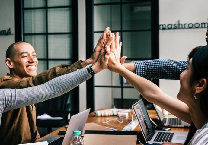 Happy colleagues high-fiving in the office-min