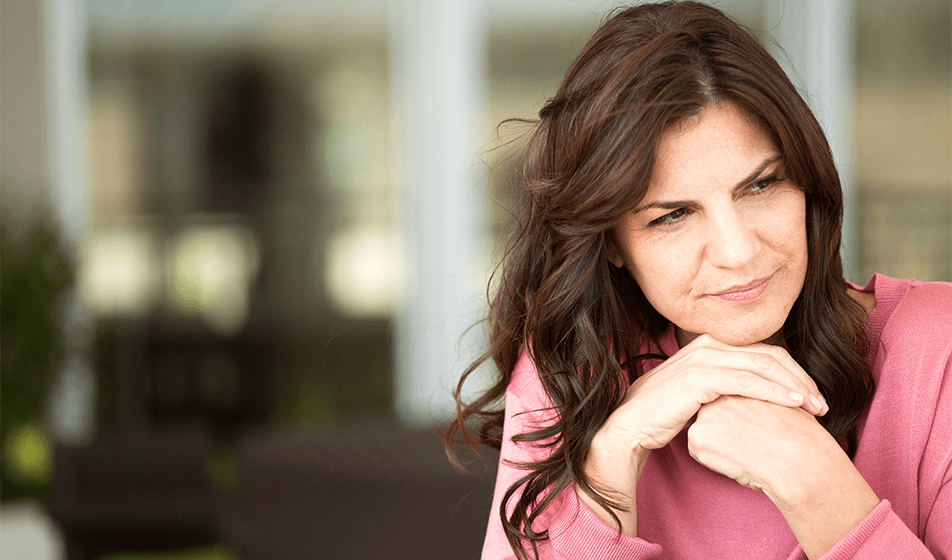 A woman looks serious as her hands are clasped under her chin