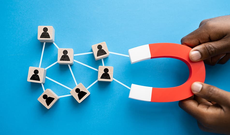 Hands are shown holding a magnet, connected by lines to individual cube blocks showing people icons, representing employees.