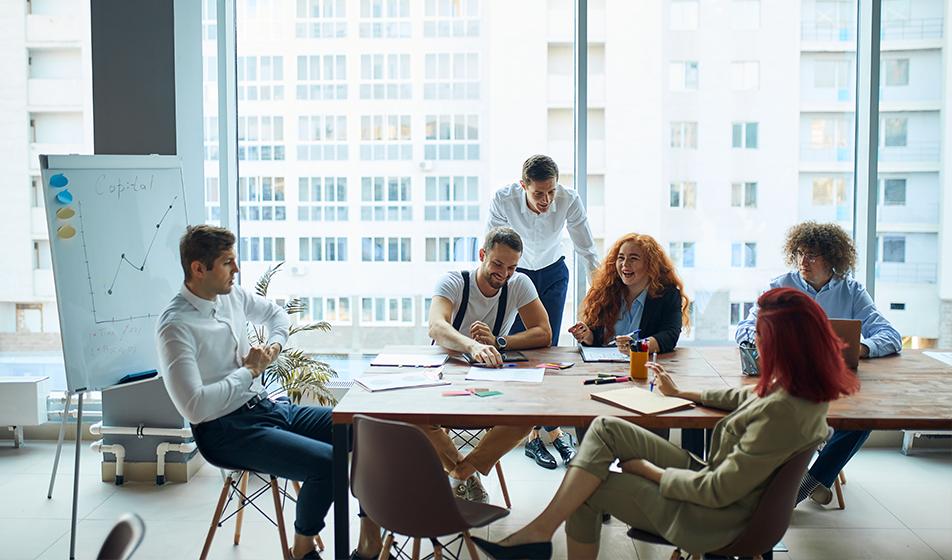 A group of people sit around a table in an office environment